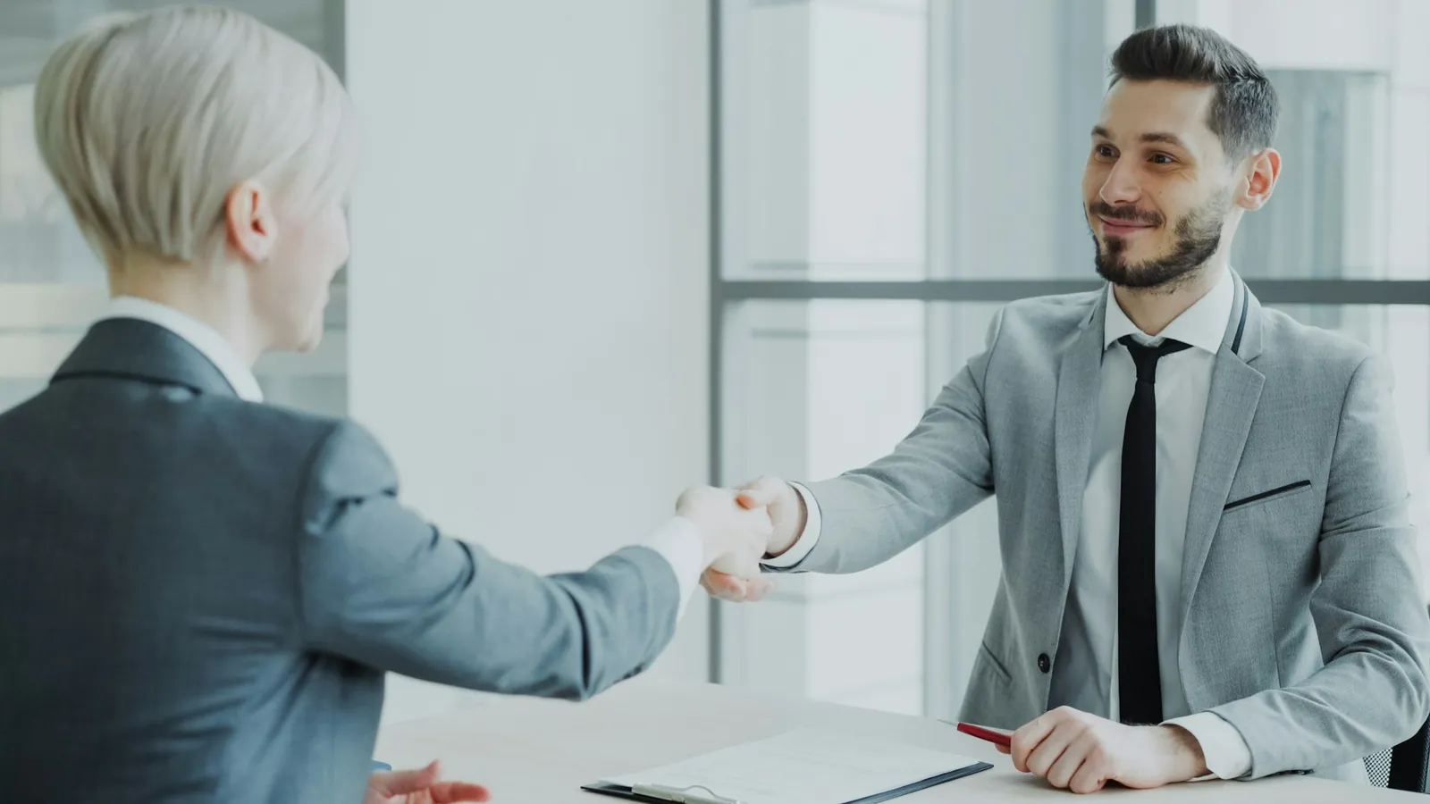 Two executives shaking hands in a bright office